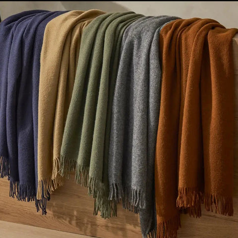 A plain green wool throw with fringe, by Weave Home