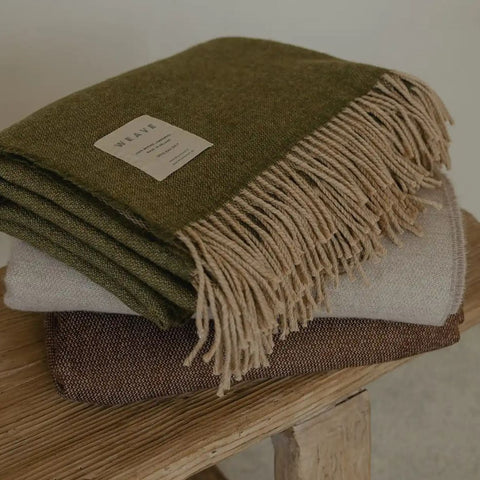 A plain green wool throw with fringe, by Weave Home