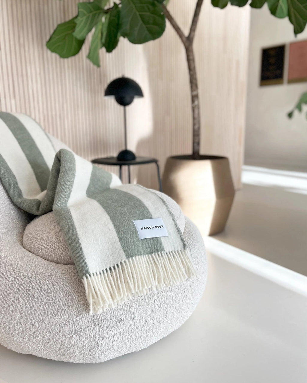 A green and pale sage striped throw, draped over a couch in a stylish living room. 