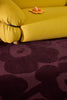 Marimekko Unikko floral patterned rug with deep burgundy flowers and a yellow couch