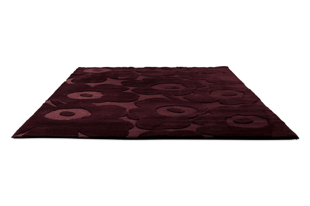 Perspective view of the Marimekko Unikko floral patterned rug with deep burgundy flowers