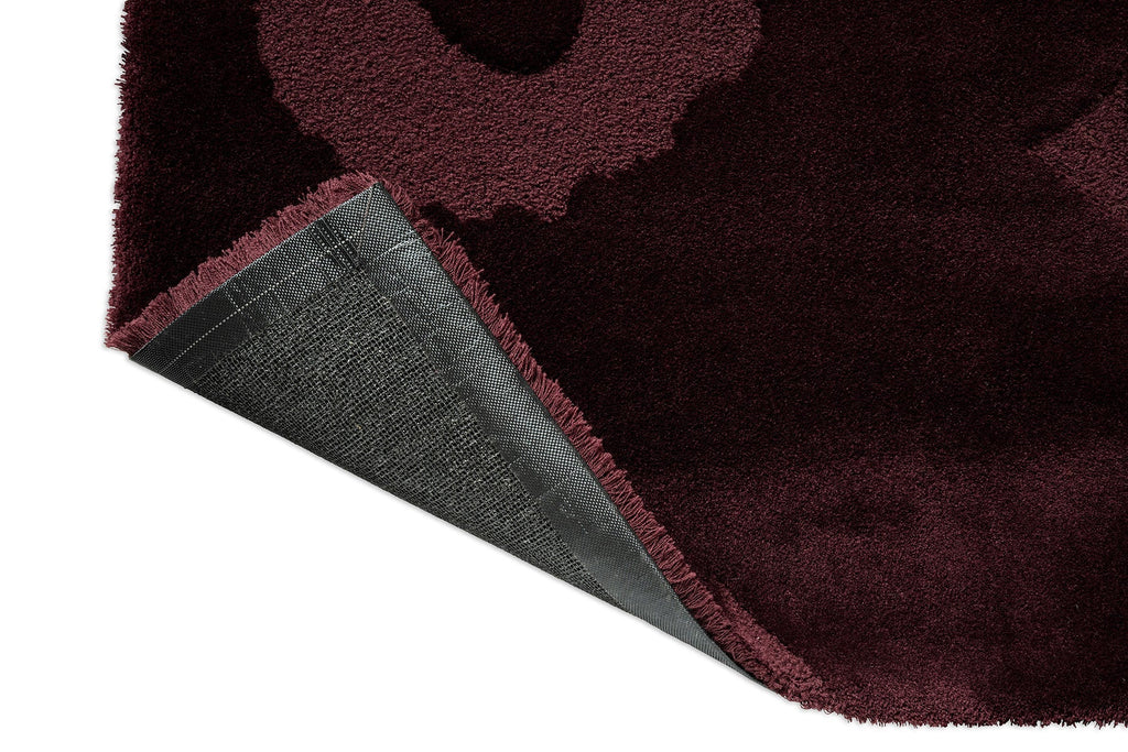 Marimekko Unikko floral patterned rug with deep burgundy flowers with corner folded to show backing