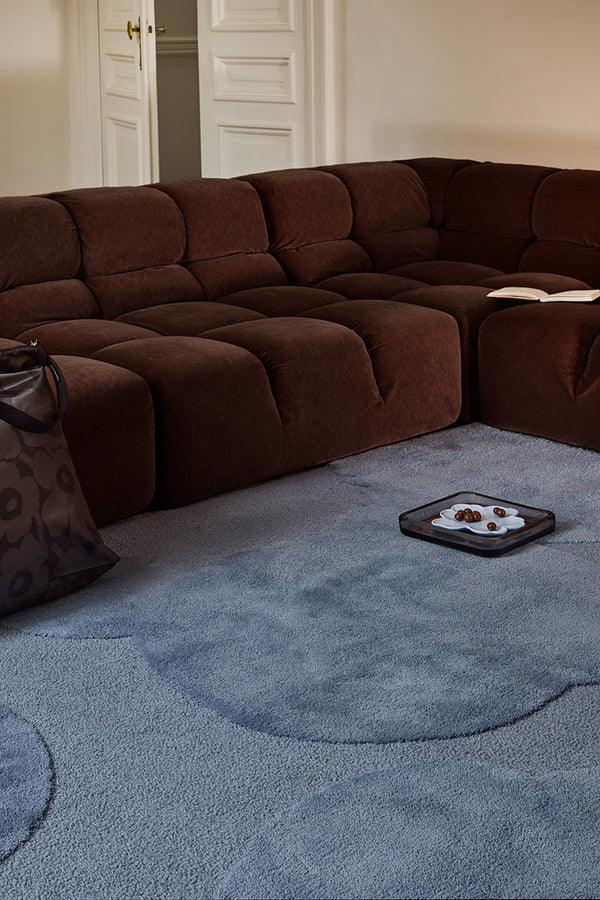Marimekko Unikko floral patterned rug with mid blue flowers in a modern living room with brown couch