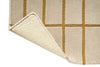 Corner of a Marimekko NZ wool beige runner rug with gold grid pattern with backing on show