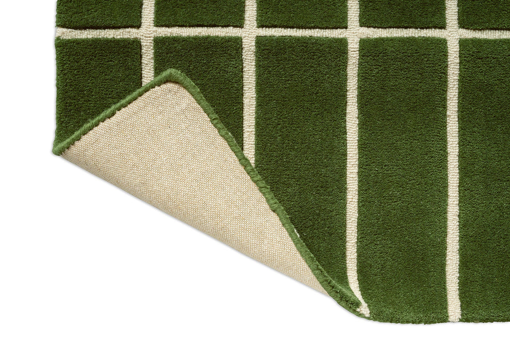 Corner view of a green geometric Marimekko NZ wool runner rug with corner folded up to show the backing