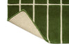 Corner view of a green geometric Marimekko NZ wool runner rug with corner folded up to show the backing