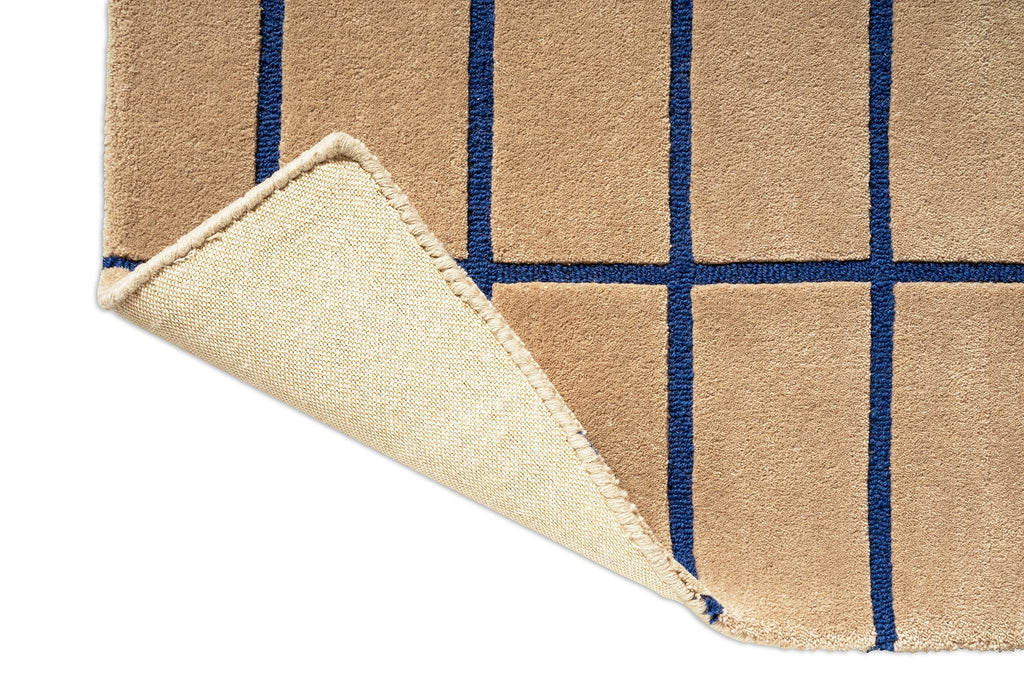 Close up of a Marimekko NZ wool runner rug with blue grid pattern and corner folded to show backing