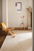 Modern interior with a gold chair, abstract art, and a creamy white Marimekko NZ wool rug 
