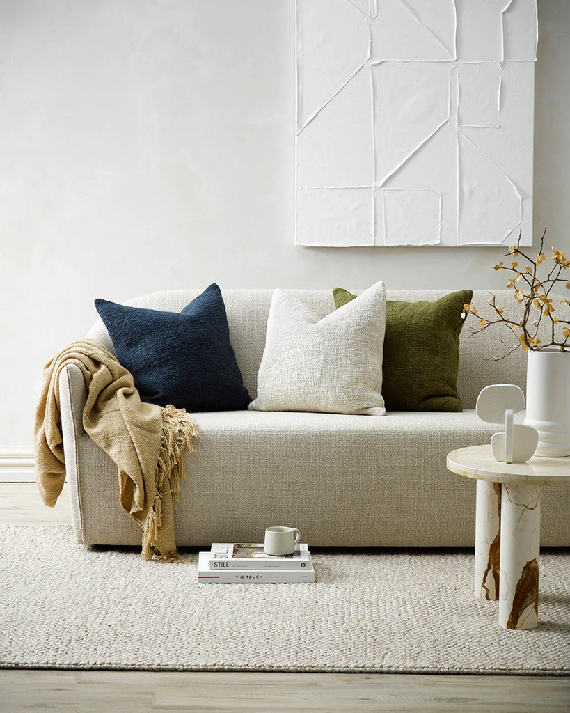 Three beautiful Baya cyprian cushion on a neutral couch in a contemporary living room
