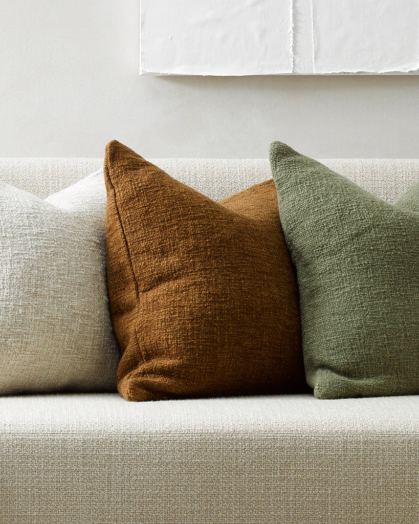Three natural toned Baya cyprian cushions on a boucle couch