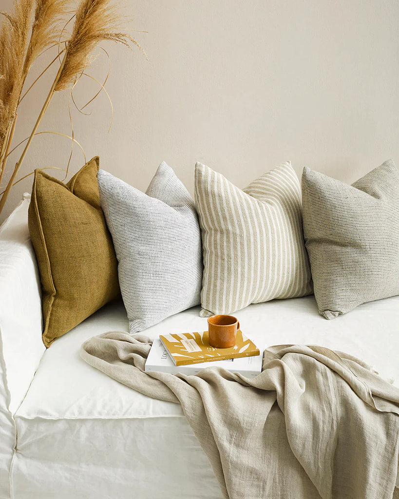 A line up of warm, neutral toned cushions on a white couch