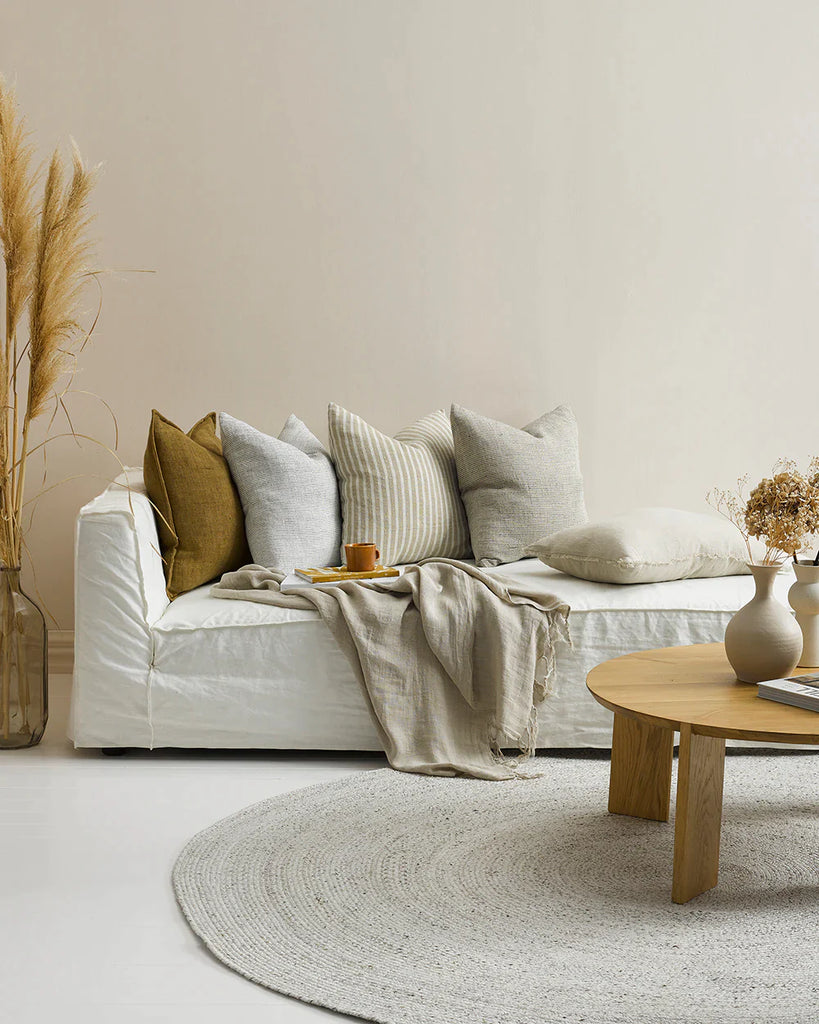 A contempory living room with a white couch and five stunning contrast linen cushions