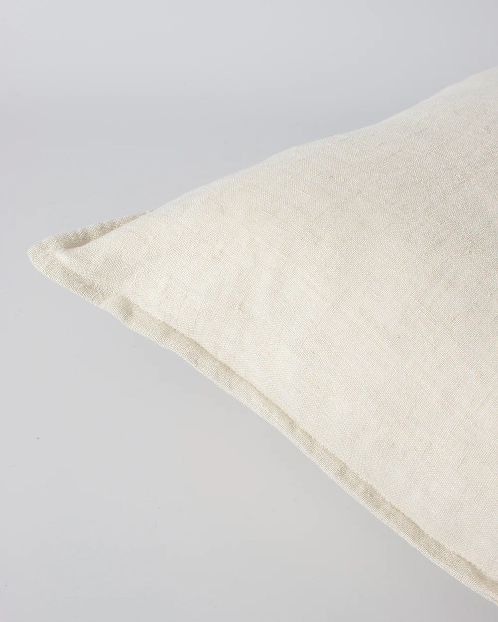 Corner detail showing flange of a cream linen cushion by Baya, the Cassia colour 'Almond'