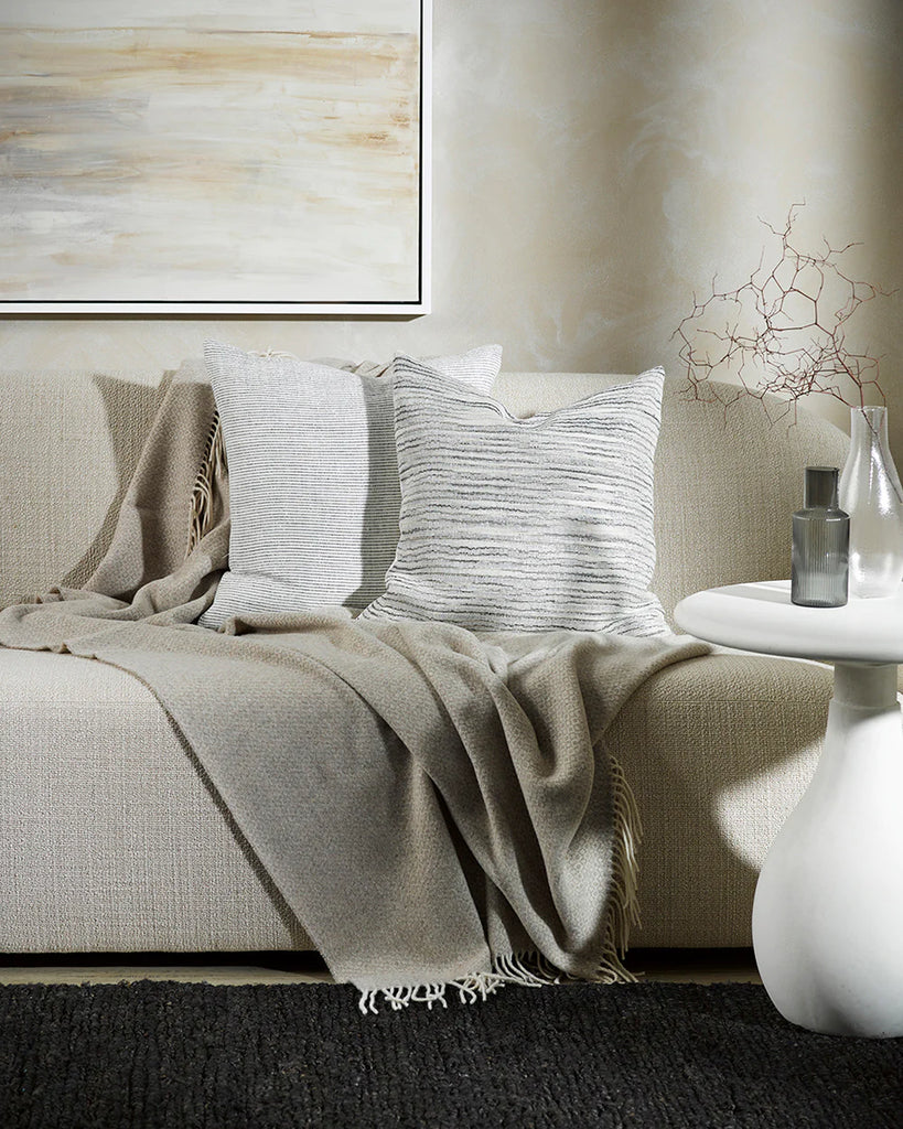 Two creamy white striped Baya cushions in a neutral living room