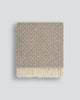 Patterned wool blanket with fringe on a light gray background