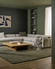 Modern living room with a gray sectional sofa, coffee table, green wool rug and patterned wool throw