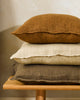 Stack of three textural linen cushions in rich warm tones
