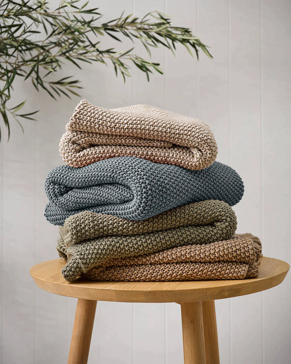 Beautiful stack of the Baya organic cotton Devon throw blankets in a home interior