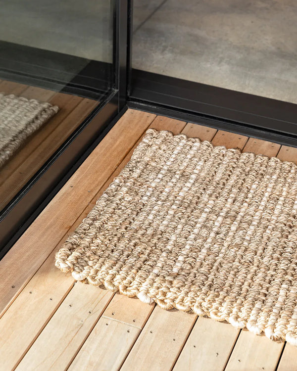 View of the Portsea Jute entrance door mat set against wooden floorboards outside a contemporary home