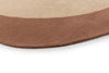 Close up of the edge of a warm brown and beige toned rug, with a curving finish. 