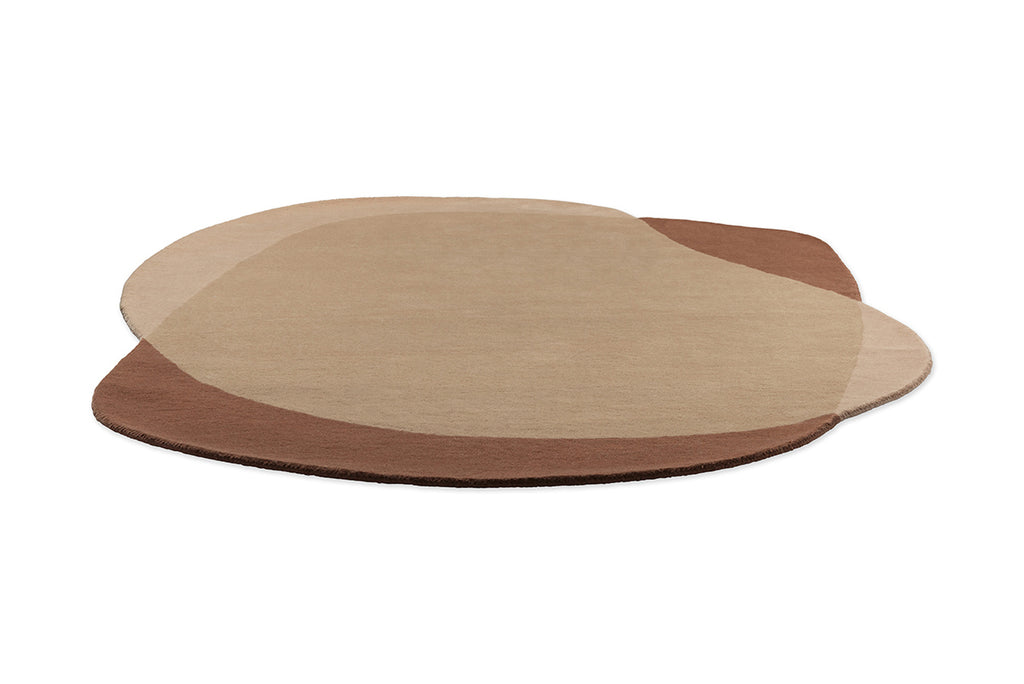 Full view from the side of a caramel and warm brown toned floor rug, in an irregular oval shape by Brink and Campman