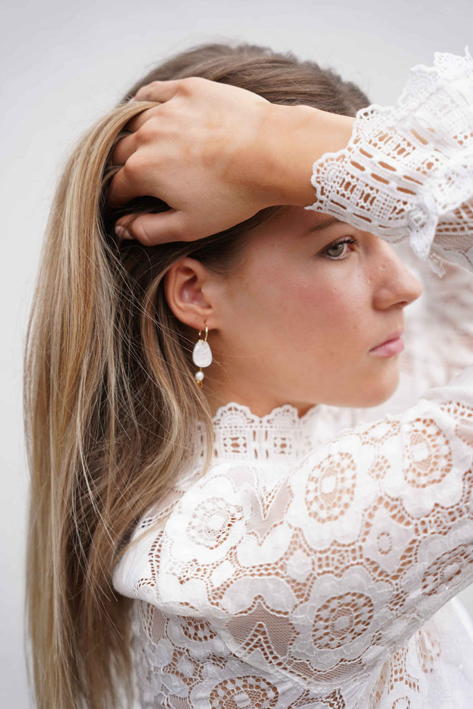 A model wearing NZ designer Hagen and Co dangle earrings feathring acrylic, glass beads, and a freshwater pearl charm
