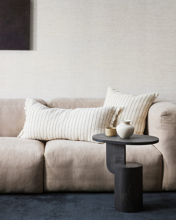 A chic interior scene featuring a cream coloured couch and two artisanal milk and midnight striped cushions by Baya NZ.  