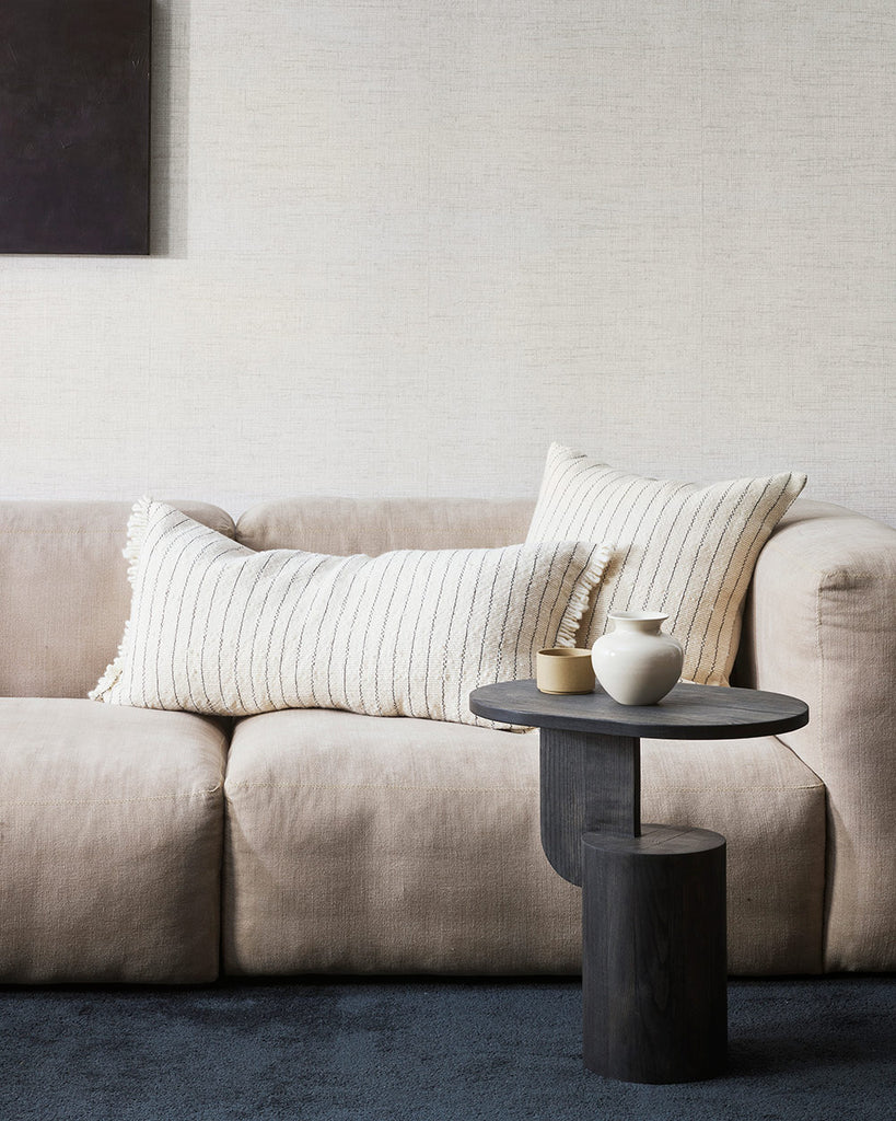 A chic interior scene featuring a cream coloured couch and two artisanal milk and midnight striped cushions by Baya NZ.  