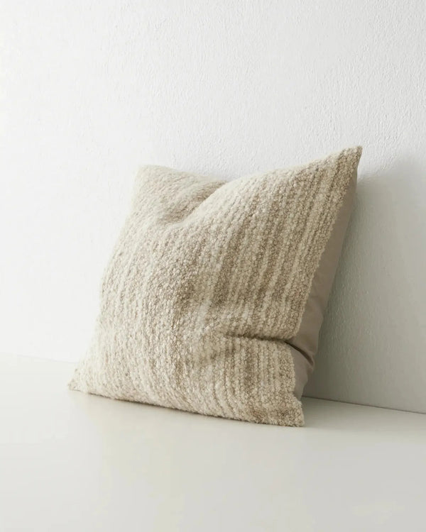 A natural, creamy beige coloured woven cushion with textural finish, seen at three quarter view