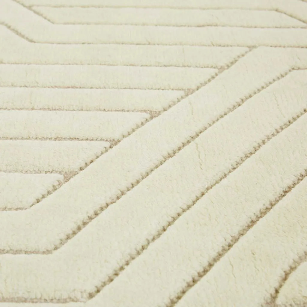 Close up of a cream/ivory wool floor rug featuring a striking geometric design