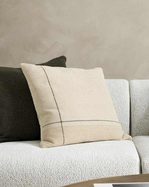 A couch styled with cushions in beige, taupe, cream and camel tones, with highlights of forest green by Baya.
