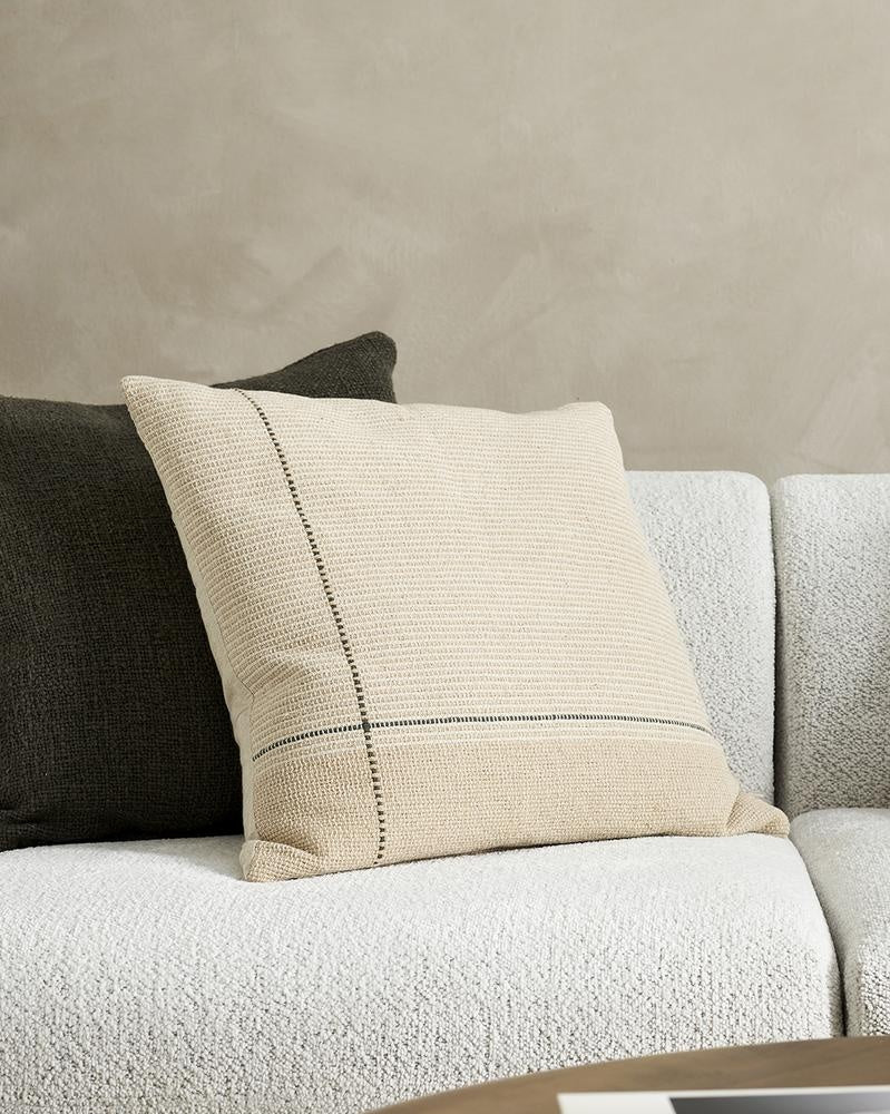 A couch styled with cushions in beige, taupe, cream and camel tones, with highlights of forest green by Baya.