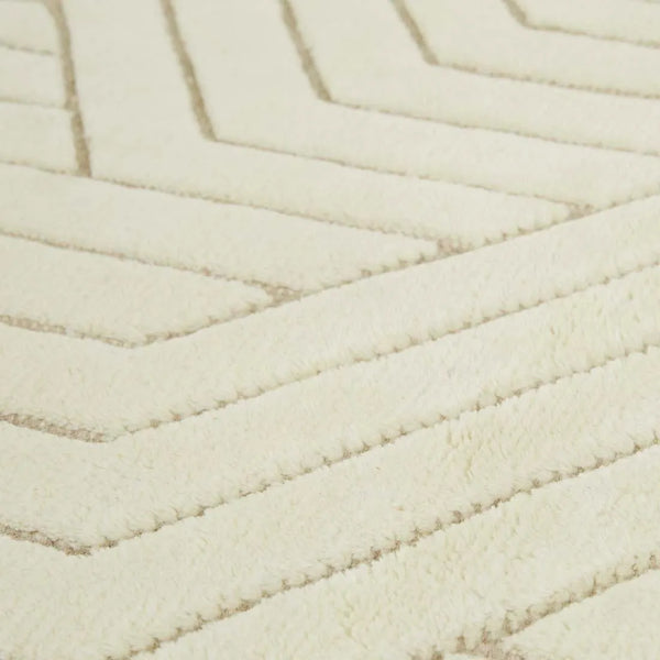 Close up of a cream/ivory wool floor rug featuring a striking geometric design