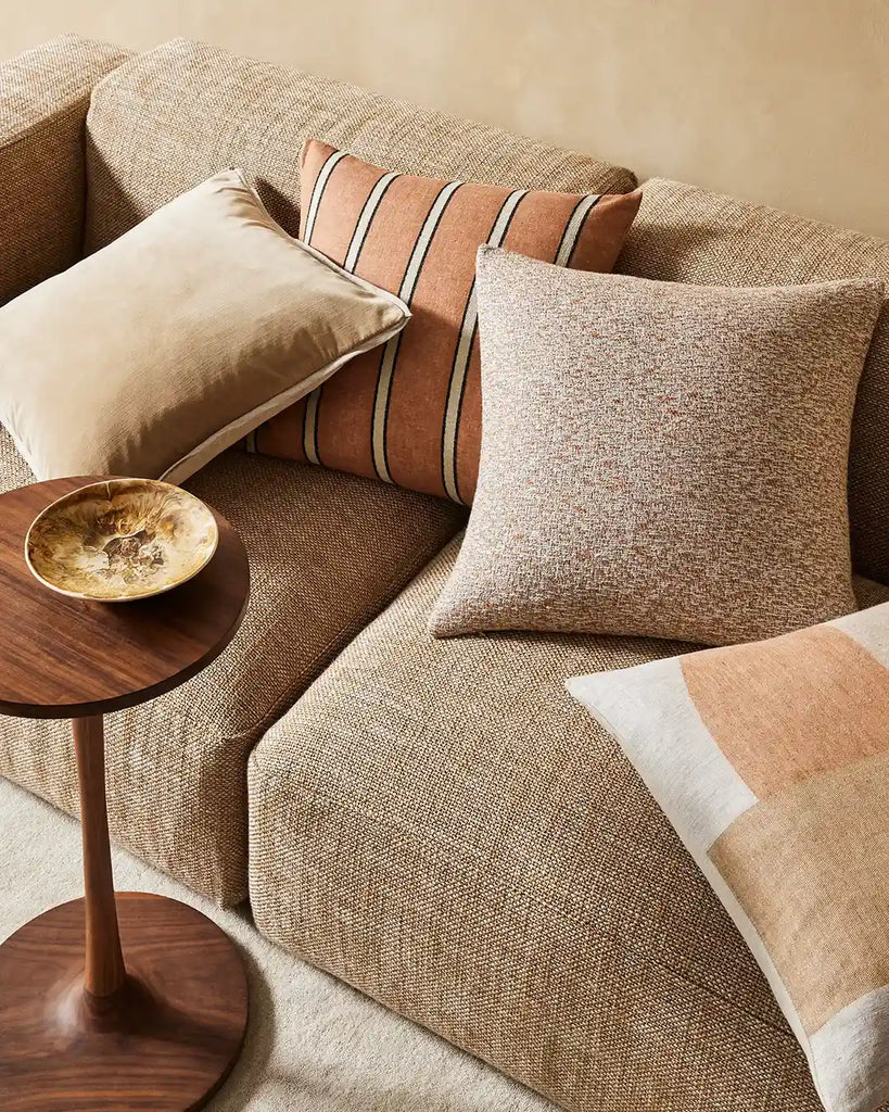 The donatella textural, brown cushion seen with other complementary cushions on a modern couch 