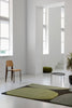 A modern green floor rug featured in a white minimalist, modern living sapce