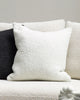 The Baya white textural cyprian cushion shown on a couch with a black contrast cushion