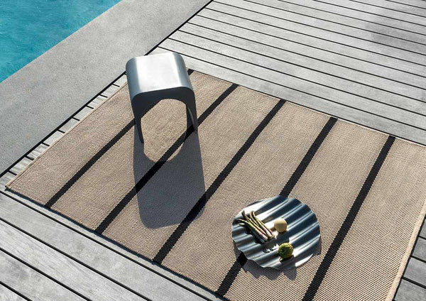 A premium, outdoor rug in a stylish black and beige stripe by Brink and Campman.
