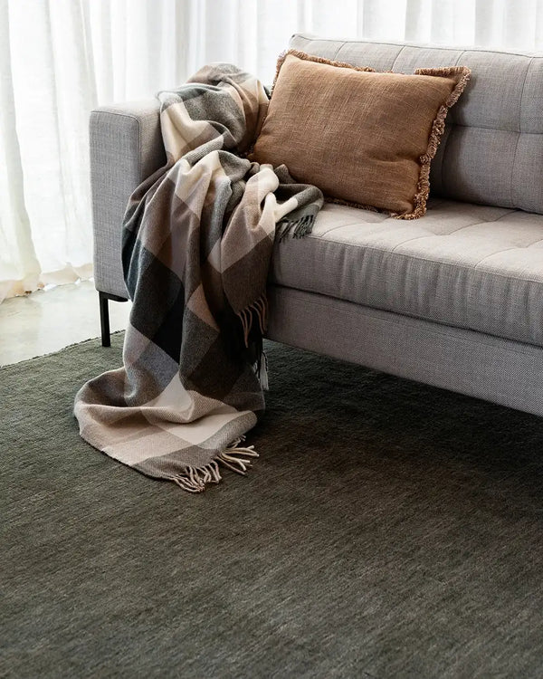 The Baya Sandringham wool rug in colour 'forest' with tasseled fringe , in a contemporary living room
