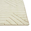 Corner of a cream/ivory wool floor rug featuring a striking geometric design