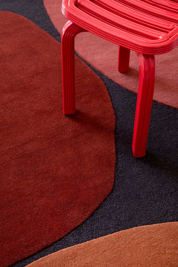 A close up of the red tones wihtin the Plateau Terra wool floor rug by Brink and Campman