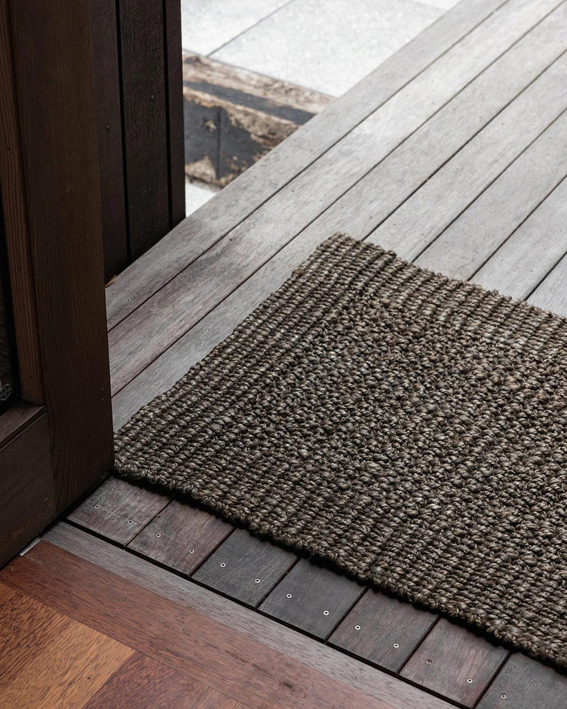 A doorway with a dark natural toned jute doormat. By Baya 