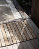 An entranceway with a striped doormat in different tones of natural jute, handwoven and designed by Baya. 