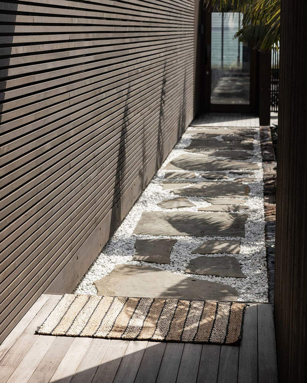 A sunny entryway with a striped jute entrance mat, made by Baya. 