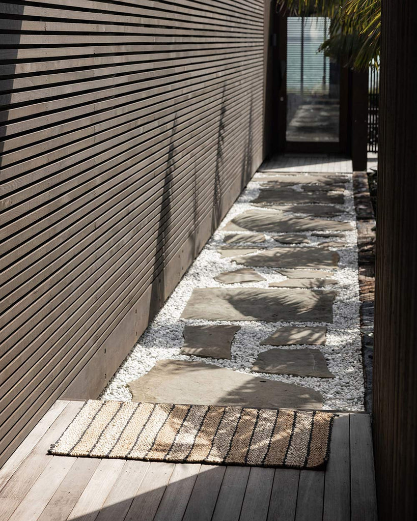 A sunny entryway with a striped jute entrance mat, made by Baya. 
