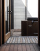 A doorway with an entrance mat made of striking striped natural handwoven jute fibres, by Baya. 