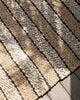 A detailed view of a striped, handwoven textural doormat by Baya, the differing stripes woven in different patterns to add sophistication. 