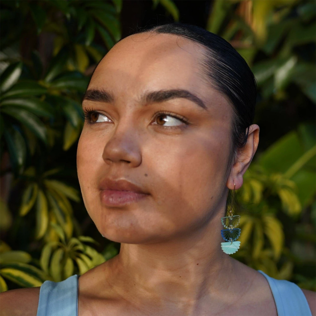 Blue and aqua dangle earrings on gold hooks, worn by a model