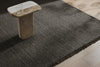 The 'Puglia' floor rug by Weave Home, in colour 'Pigeon" - a deep cool-toned brown - seen on floor, highlighting the fringed edge.
