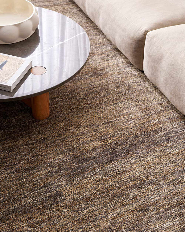 A stylish modern living room with a textural bamboo silk and jute floor rug in shades of warm grey and natural jute brown, by Baya