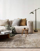 A living room with a textured handmade floor rug in shades of warm grey and honey brown, made with natural jute fibres  and bamboo silk by Baya. 